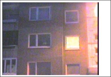 Nerenovuotas daugiabutis Medeinos g. 31, fasadas vakare, vienas langas ryškiai apšviestas.