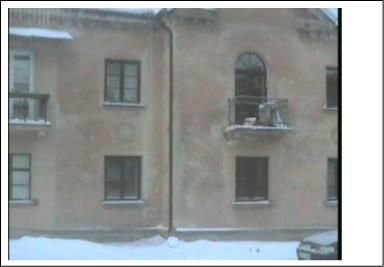 Nerenovuoto dviejų aukštų daugiabučio Treinio g. 5 nuotrauka žiemą, matomi balkonai, langai ir įtrūkusi sienos siūlė, atitinkanti termovizijoje žymėtą šilumos nuotėkio vietą.
